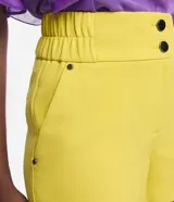 Bermuda roja de poliéster con cintura elástica, bolsillos laterales y cierre con cremallera y botones.