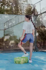 Short biker de lycra azul con franjas laterales rojas y bolsillo para pelotas de tenis.