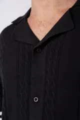 Camisa de punto de manga corta con cuello tipo bowling y cierre frontal de botones. Presenta un diseño texturizado con franjas verticales y detalles de contraste en blanco en los bordes de las mangas.