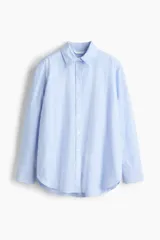 Camisa de corte relajado con diseño a rayas finas en tonos celeste y blanco, cuello clásico, mangas largas con puños anchos abotonados y bajo redondeado.