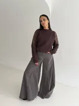 Sweater negro de tejido de punto con cuello redondo y mangas largas. Presenta detalles de transparencias y apliques bordados con pedrería en la parte superior de las mangas.