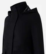 Campera alargada de polivelour color beige, con capucha, cierre frontal con botones a presión y bolsillos con solapa. Presenta un diseño de corte recto y manga larga.