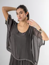 Vestido largo de seda italiana en color gris oscuro, con falda larga lisa, forro y cintura elastizada. Posee una sobrecapa con detalles de paillettes en los bordes de las mangas y la cintura.