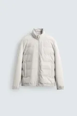 Cazadora acolchada de cuello subido, color negro, con mangas largas de tejido elástico. Incluye bolsillos en la cadera, un bolsillo interior y bajo con elástico. Cierre frontal de cremallera.