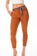 Pantalón de vestir color terracota, de corte ajustado, con cintura plisada, bolsillos laterales y cinturón estampado con lazo.
