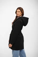 Tapado negro de corte cruzado con solapas amplias, capucha integrada y lazo ajustable en la cintura. Presenta cierre frontal con botones y bolsillos laterales.