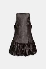 Vestido corto de efecto piel con cuello barco y diseño sin mangas. Presenta un bajo abullonado con elástico interior y cierre de cremallera en la espalda.