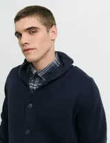 Cardigan de punto azul marino con cuello esmoquin, cierre frontal con botones y coderas en contraste.