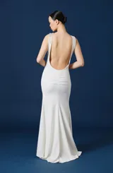 Vestido largo negro de corte sirena y silueta ajustada, con detalle de aplique floral brillante en el hombro izquierdo.