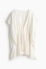 Vestido corto estilo túnica color blanco, de diseño oversized y mangas cortas, con escote en V pronunciado y cordón ajustable en la cintura.