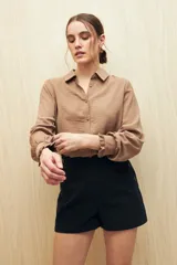 Camisa color café con textura sutil, cuello clásico, botones forrados a tono y mangas largas con puños fruncidos.