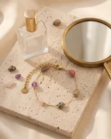 Pulsera de cadena fina con baño de oro, adornada con cuentas de piedras naturales en tonos variados, incluyendo jaspe dálmata y amatista.