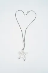 Collar con dije de estrella de mar plateada con textura martillada, suspendido de un cordón gris ajustable.