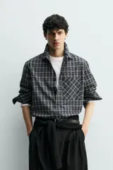 Camisa de corte relajado confeccionada en voile de algodón, con estampado de cuadros. Presenta cuello solapa, manga larga con puños abotonados, bolsillo de parche en el pecho y cierre frontal de botones.