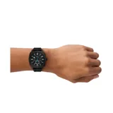 Reloj Fossil Machine para hombre, con caja redonda de acero inoxidable negro, esfera negra con detalles en azul y correa de silicona negra con textura.