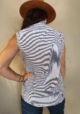 Musculosa tipo camisa con cuello camisero, cierre frontal de botones y dos bolsillos delanteros en el pecho. Diseño a rayas verticales en tonos celeste y blanco.