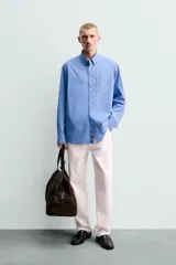 Camisa de corte regular fit confeccionada en tejido de algodón de color azul. Cuenta con cuello solapa, manga larga con puño abotonado, bolsillo de parche en el pecho y cierre frontal con botones.