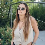 Chaleco corto con estampado abstracto en tonos dorados y azules, escote en V y cierre frontal con botones de madera.