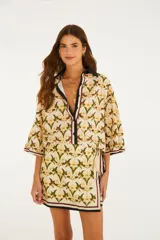 Camisa de algodón con estampado floral y de aves, cuello camisero oscuro y cierre frontal parcial con botones. Mangas amplias de largo codo con ribetes en contraste.
