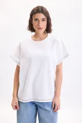 Camiseta blanca de manga corta con corte holgado y costuras decorativas con pespuntes en color negro.