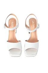 Sandalias de cuero blanco con plataforma y taco alto grueso, tira ancha en la parte delantera y tiras finas con hebilla en el tobillo.