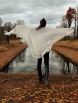 Ruana color crudo de tejido de punto grueso con flecos.