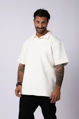 Chomba de manga corta con cuello polo, confeccionada en tejido de punto acanalado de textura pesada. Presenta un calce relajado y cuenta con una pequeña etiqueta distintiva en el ruedo.