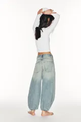 Jeans de mezclilla de tiro medio con diseño amplio tipo balloon, costuras marcadas y bajo con puño elástico. Cuenta con bolsillos delanteros y traseros, y cierre frontal con cremallera y botón metálico.