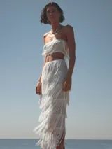 Conjunto de top bandeau y falda midi, ambos blancos con flecos.
