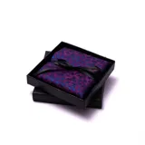Pañuelo de bolsillo de microfibra con estampado floral en tonos violeta y azul, presentado en caja de regalo negra con cinta.