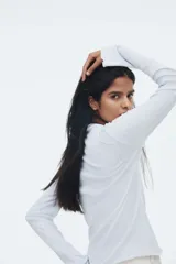 Top ajustado de punto acanalado suave, color celeste, con cuello alto y mangas largas acampanadas.