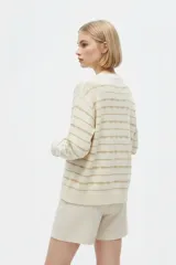 Sweater de punto color blanco con diseño de rayas horizontales doradas, cuello redondo y manga larga.