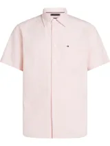 Camisa de manga corta Tommy Hilfiger confeccionada en tejido oxford de algodón. Presenta un diseño de rayas verticales finas en color rosa y blanco, cuello clásico con botones, cierre frontal abotonado y un bolsillo en el pecho con el logo de la marca bordado.