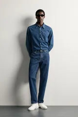 Jeans regular fit de tiro medio, confeccionados en denim de algodón azul oscuro con efecto lavado. Presenta diseño clásico de cinco bolsillos, pierna recta y cierre frontal con cremallera y botón.