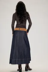 Falda midi de denim azul oscuro con costuras a la vista en contraste. Presenta un diseño de corte recto con paneles verticales y un cinturón de gamuza en tono tostado con hebilla metálica.