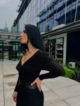 Blusa negra con escote off-shoulder y mangas largas ajustadas.