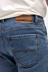 Jean de corte slim, ajustado desde la cadera hasta los tobillos, en color azul medio con acabado clásico.