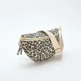 Riñonera de diseño acolchado con estampado animal print de leopardo, cierre superior con cremallera metálica y correa ajustable de lona en color crudo.