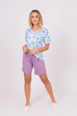 Pijama de dos piezas, compuesto por una remera de manga corta con botones y estampado de flores en tonos celeste, azul y lila, y un short lila con cintura elástica.