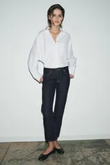 Jeans de tiro medio con corte slim leg, confeccionados en denim color beige. Presentan cintura con trabillas, diseño clásico de cinco bolsillos y cierre frontal con cremallera y botón metálico.