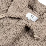 Tapado de textura tipo corderito en color taupe, con diseño de corte recto y largo. Presenta detalles de paneles lisos en los laterales y en las mangas, cuello con solapas y cierre frontal.