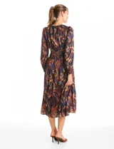 Vestido midi de manga larga con escote en V, confeccionado en tela fluida con estampado abstracto multicolor. Presenta una cintura elástica fruncida que define la silueta y una falda con caída suave y movimiento.