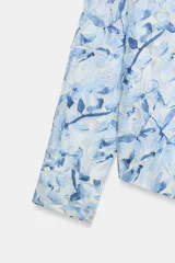 Camisa de manga larga con cuello solapa y cierre frontal de botones, confeccionada en tejido combinado semitransparente con estampado floral en tonos azules y blancos.