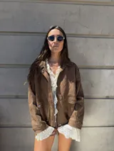 Campera marrón de gamuza sintética con cierre frontal, cuello camisero y bolsillos con solapa en el pecho.