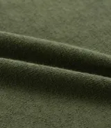 Remera verde militar de algodón texturizado, corte regular, cuello redondo y mangas cortas. Estampa tropical de una casa y palmeras en el pecho.