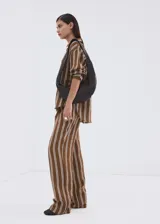 Pantalón tiro medio de corte recto con diseño estampado a rayas, detalle de pinzas, bolsillos laterales y cierre oculto con ganchos y cremallera.