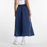 Pollera midi New Balance de tejido ripstop color azul marino, con cintura elástica, bolsillos laterales y detalles de líneas blancas en contraste. Presenta el logo de la marca en la parte inferior.