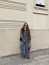 Conjunto de dos piezas compuesto por una camisa de corte oversize con bolsillos frontales y un pantalón de tiro alto con pierna ancha, ambos confeccionados en tela de viyela con estampado de cuadros en tonos marrones y beige.