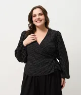 Blusa de crepé con estampado de lunares, diseño cruzado con escote en V, mangas largas con puños elásticos y lazo lateral ajustable. Incluye forro interno.