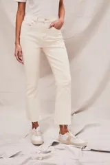 Pantalón de jean color crudo, tiro alto, corte flare y ruedo desflecado.